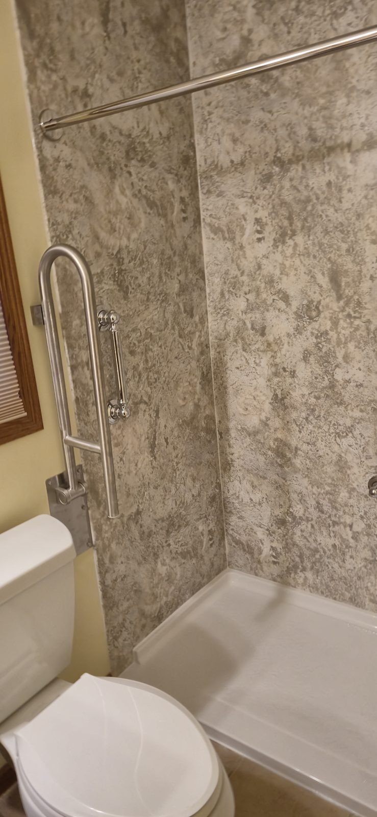 Fixed and fold-up grab bars installed next to the toilet