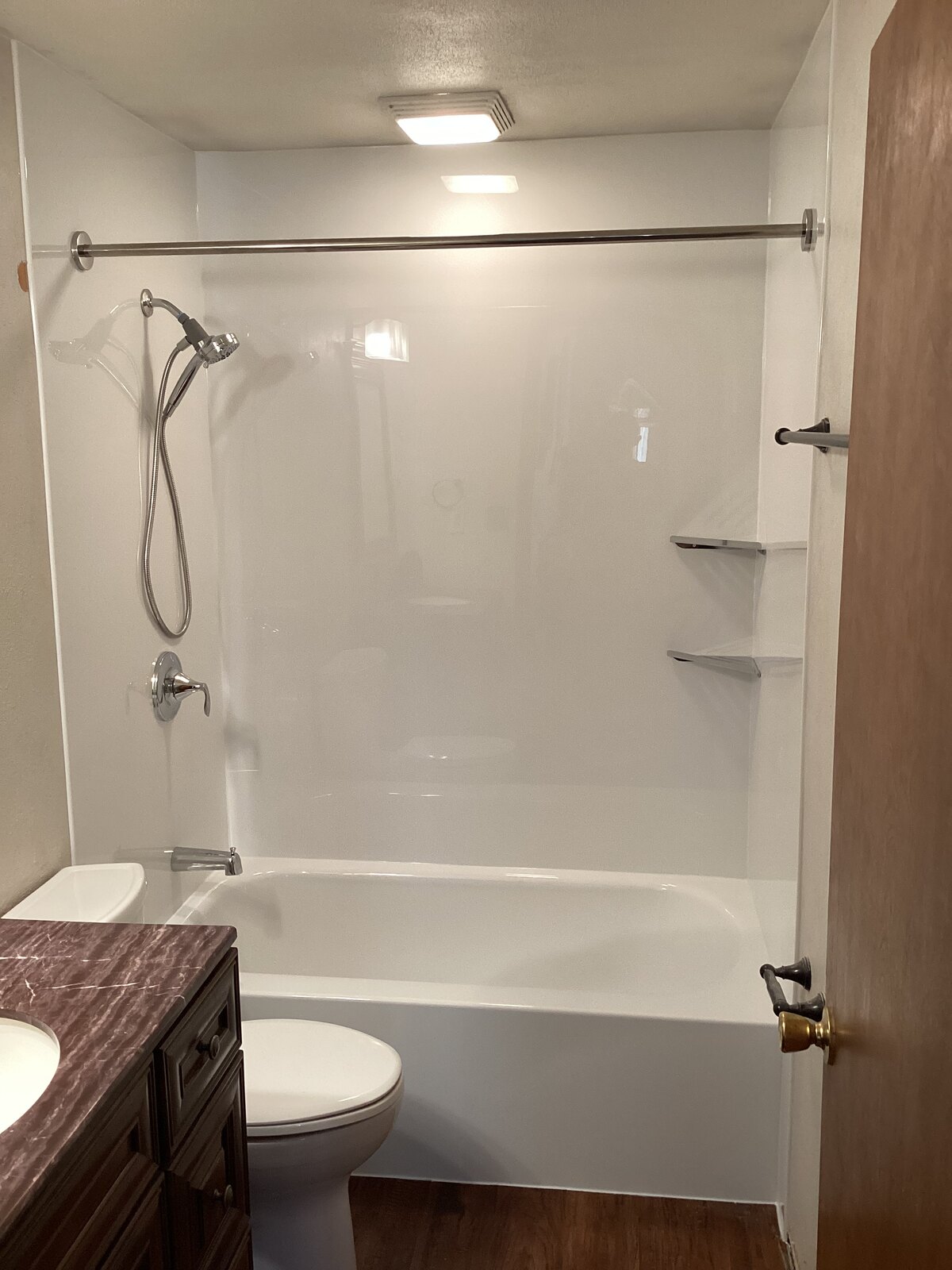 Finished replacement bathtub with stone-look surround and oil-rubbed bronze grab bars