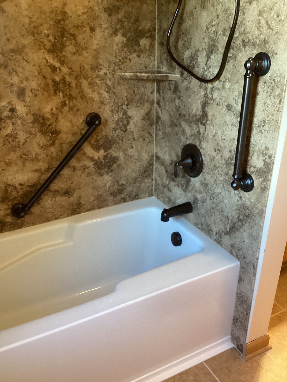 Finished replacement bathtub with stone-look surround and oil-rubbed bronze fixtures