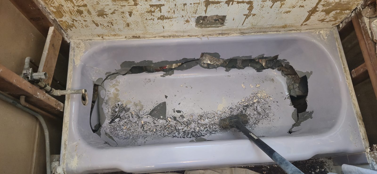 Breaking apart an old cast-iron tub in place for removal