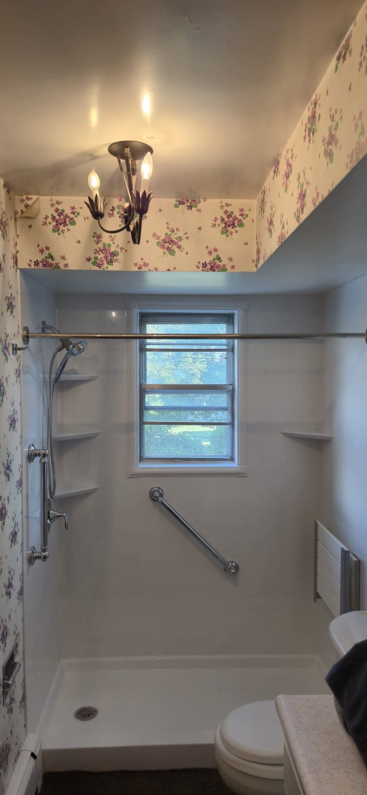 Finished low-entry shower with grab bar and corner shelves after the cast-iron tub was removed