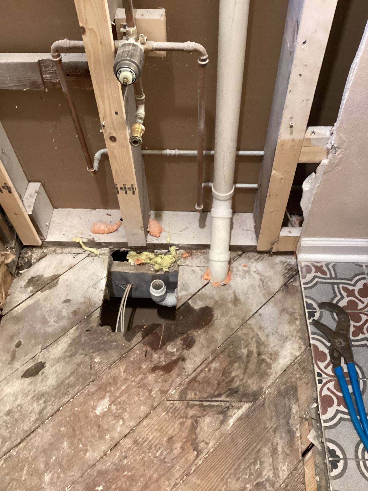 Open wall showing the old tub drain and vent being converted for the new shower