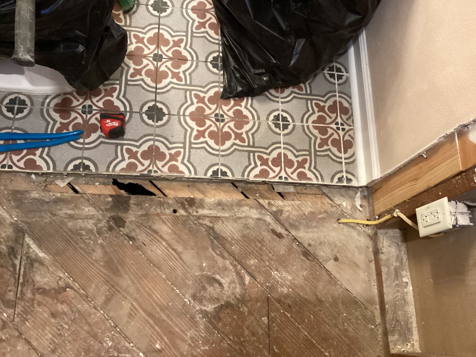 Layered old flooring cut back to the wood subfloor during the tub-to-shower conversion