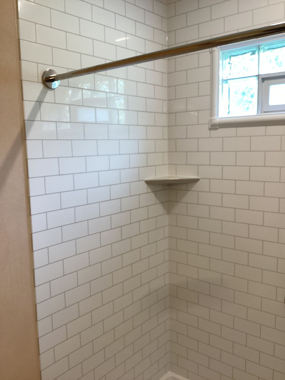 Finished shower with white subway-style wall surround and built-in shelf