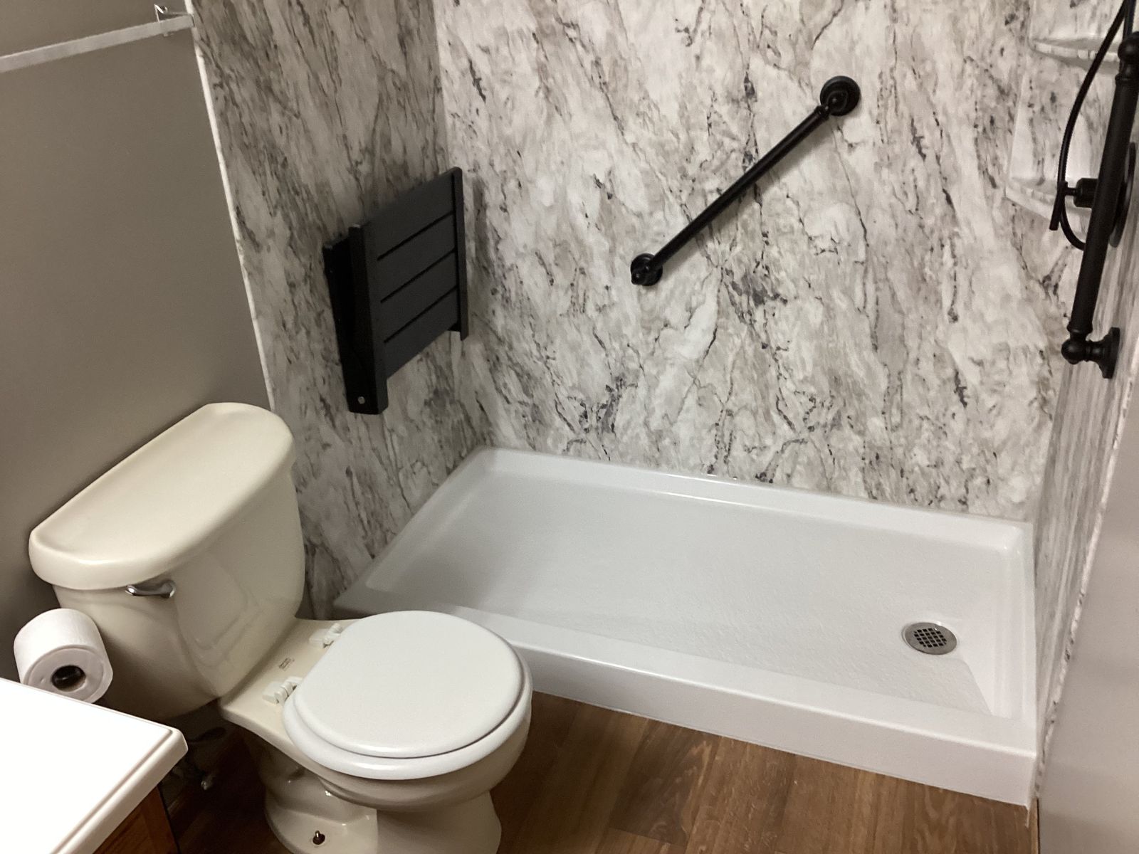 Low-threshold shower with a fold-down bench and grab bar