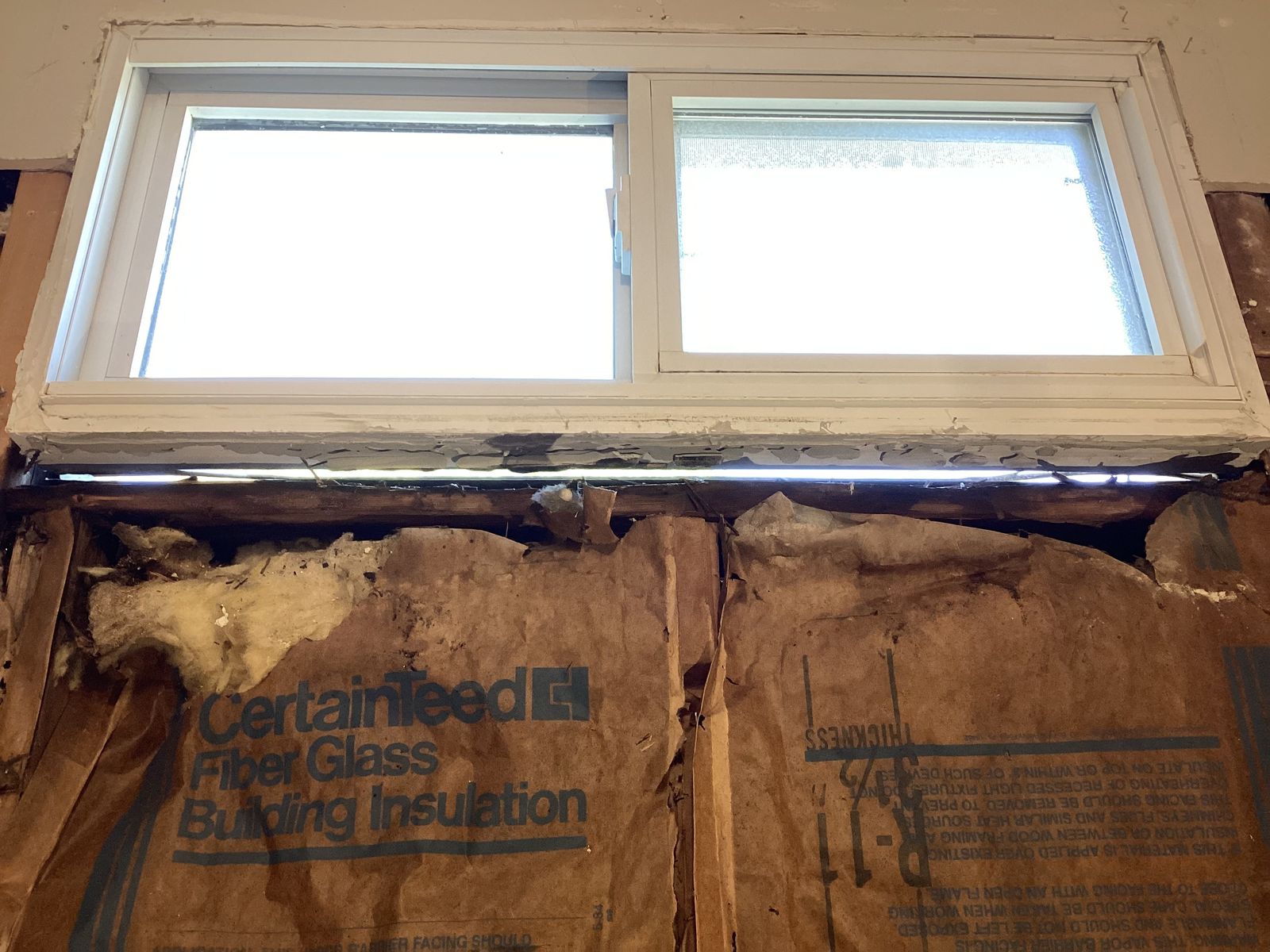 Exposed window framing and old insulation during demolition