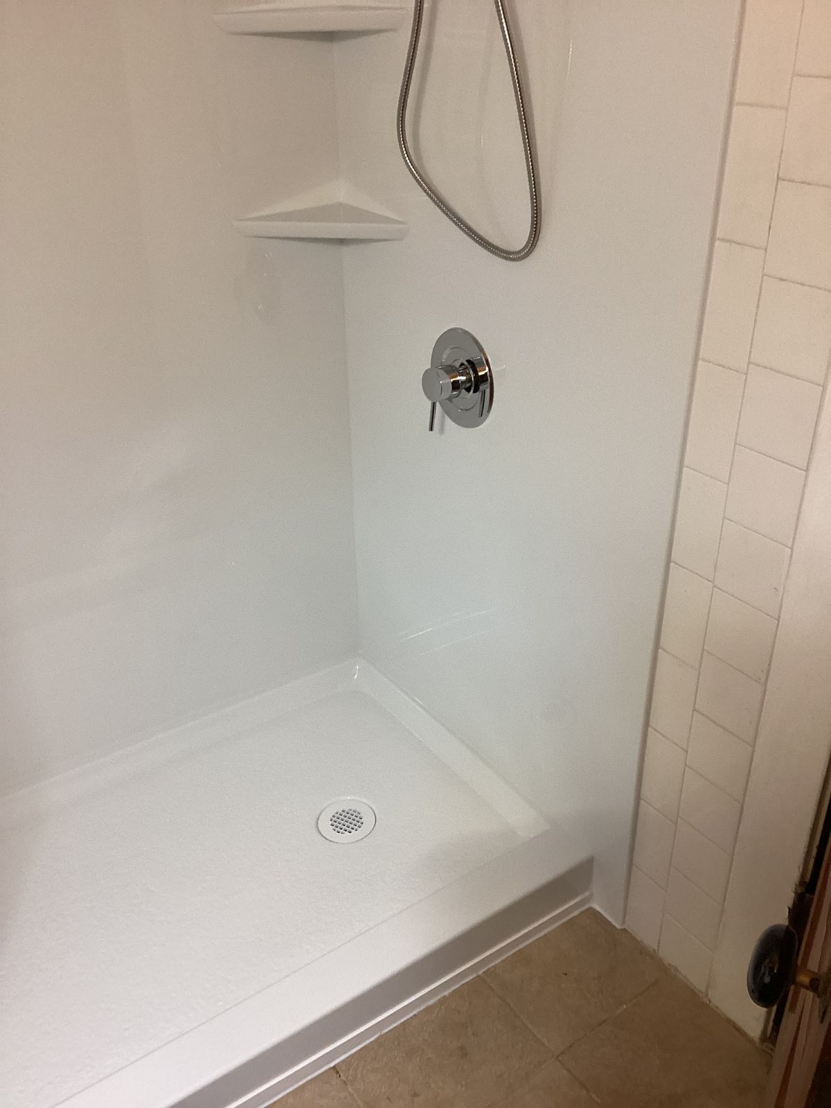 Finished shower with handheld shower head and clean wall panels