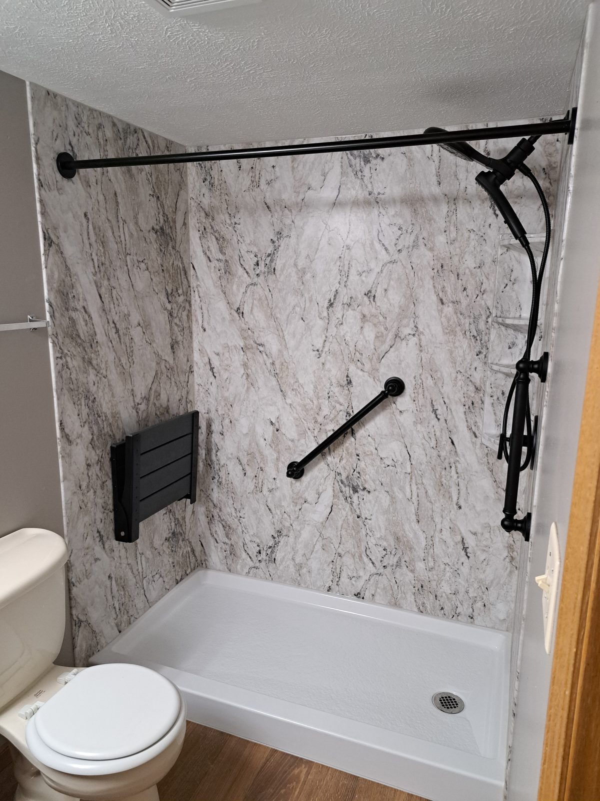 Marble-look shower with a fold-down bench and two grab bars