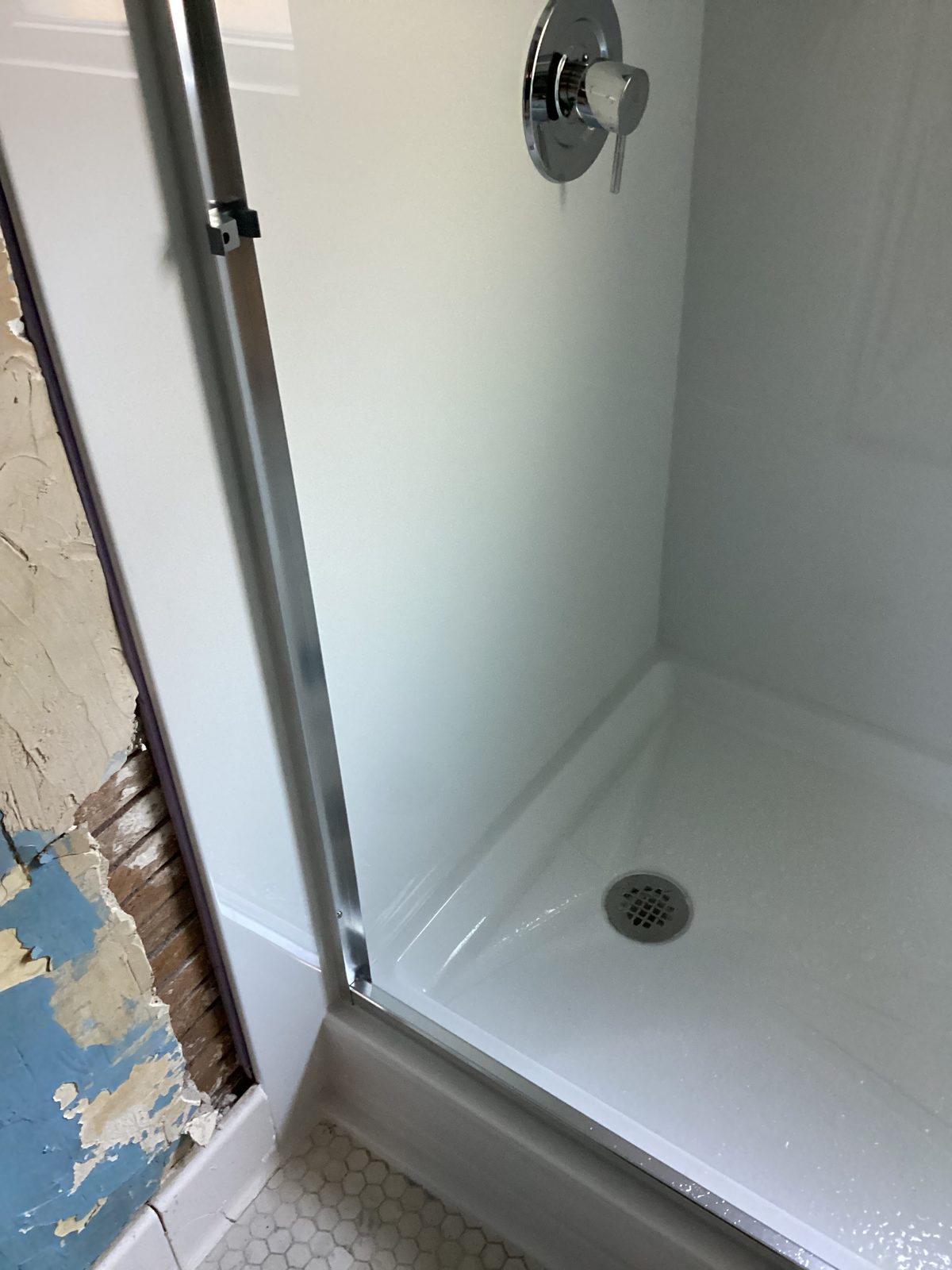 Finished shower base and wall surround beside the original hex floor