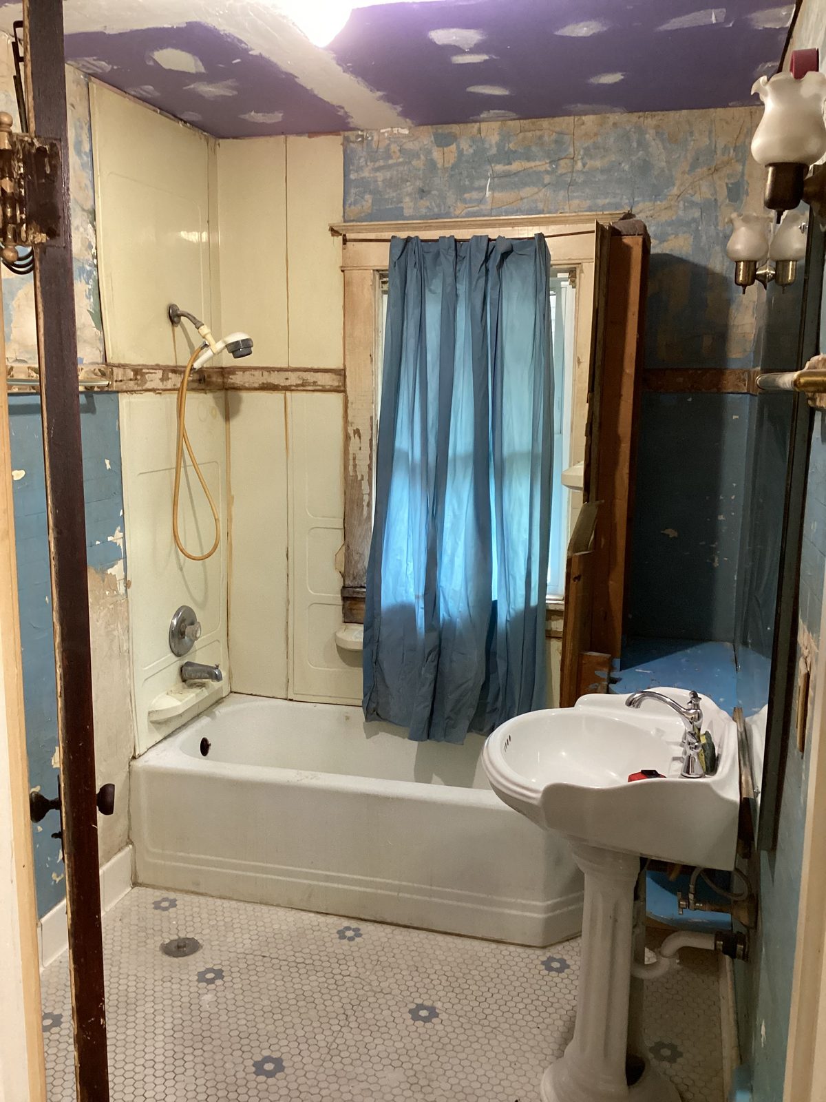 Older bathroom with a bathtub, dated tub surround and hex floor tile before the conversion