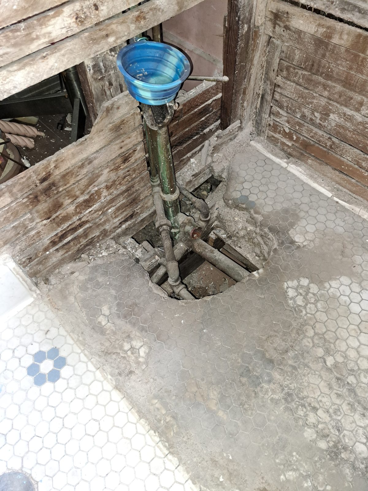 Wood wall boards and piping exposed at the old tub location