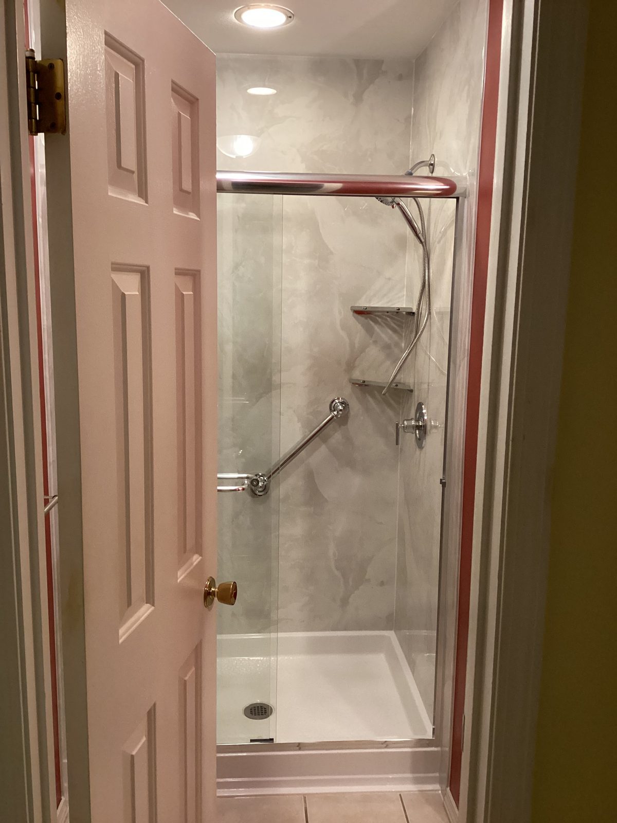 Marble-look shower with sliding glass doors seen from the bathroom doorway
