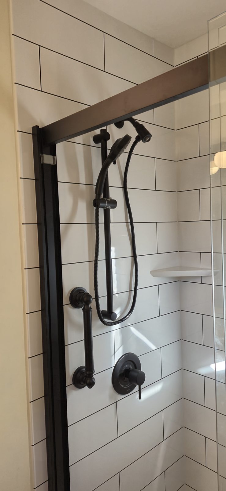 Matte black handheld shower head and slide bar against white subway tile