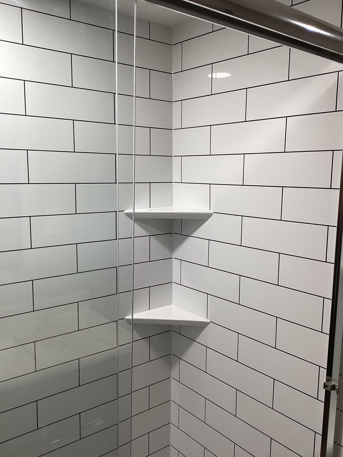 Built-in corner shelves in a white subway tile shower
