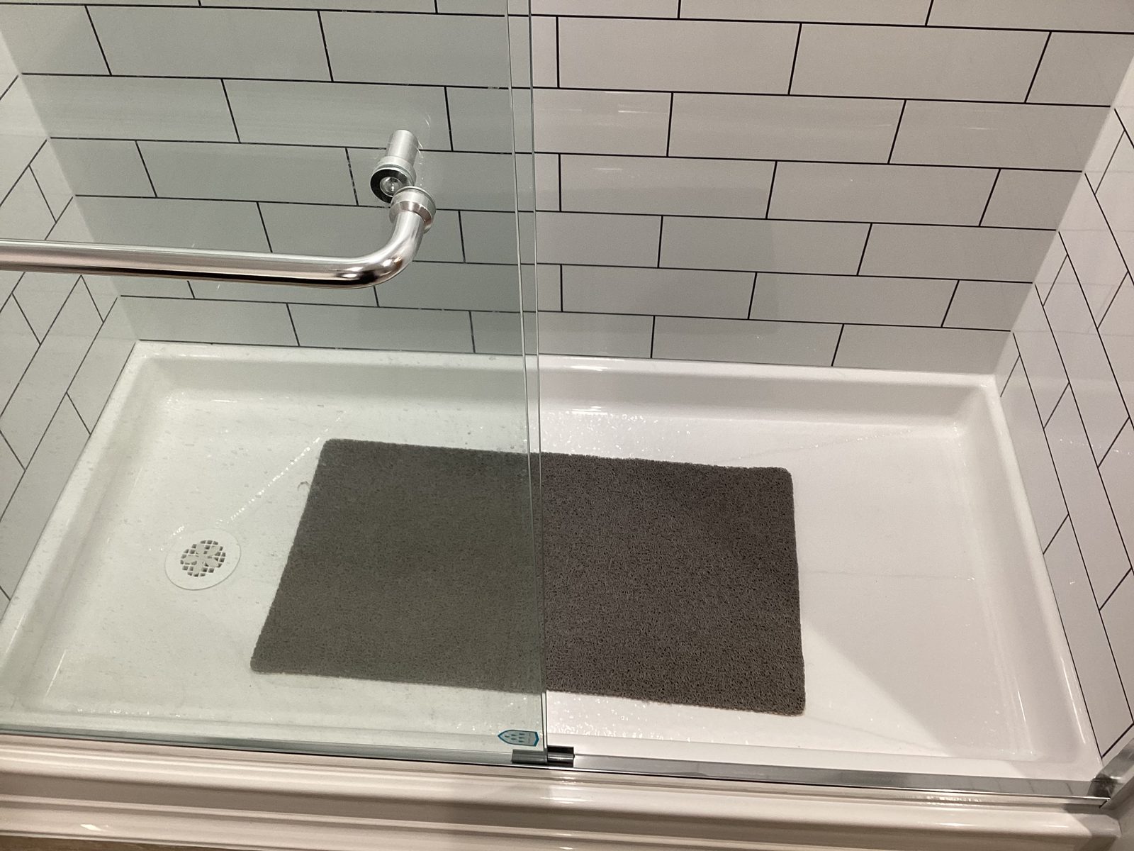 Chrome towel bar and glass sliding door on a white subway tile shower