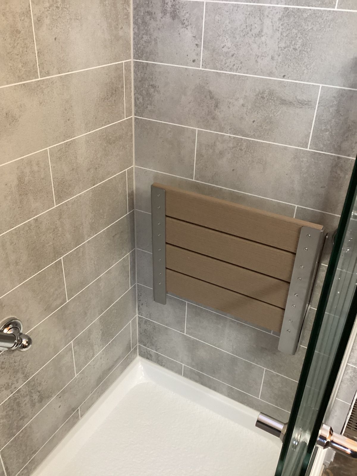 Gray subway tile-look shower wall and floor with built-in bench seat