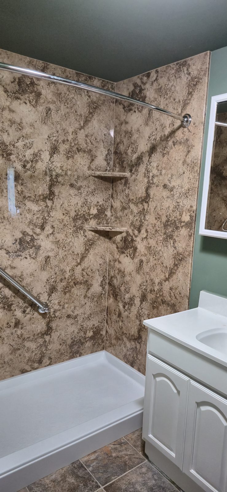 Built-in corner shelves and grab bar in a marble-look shower